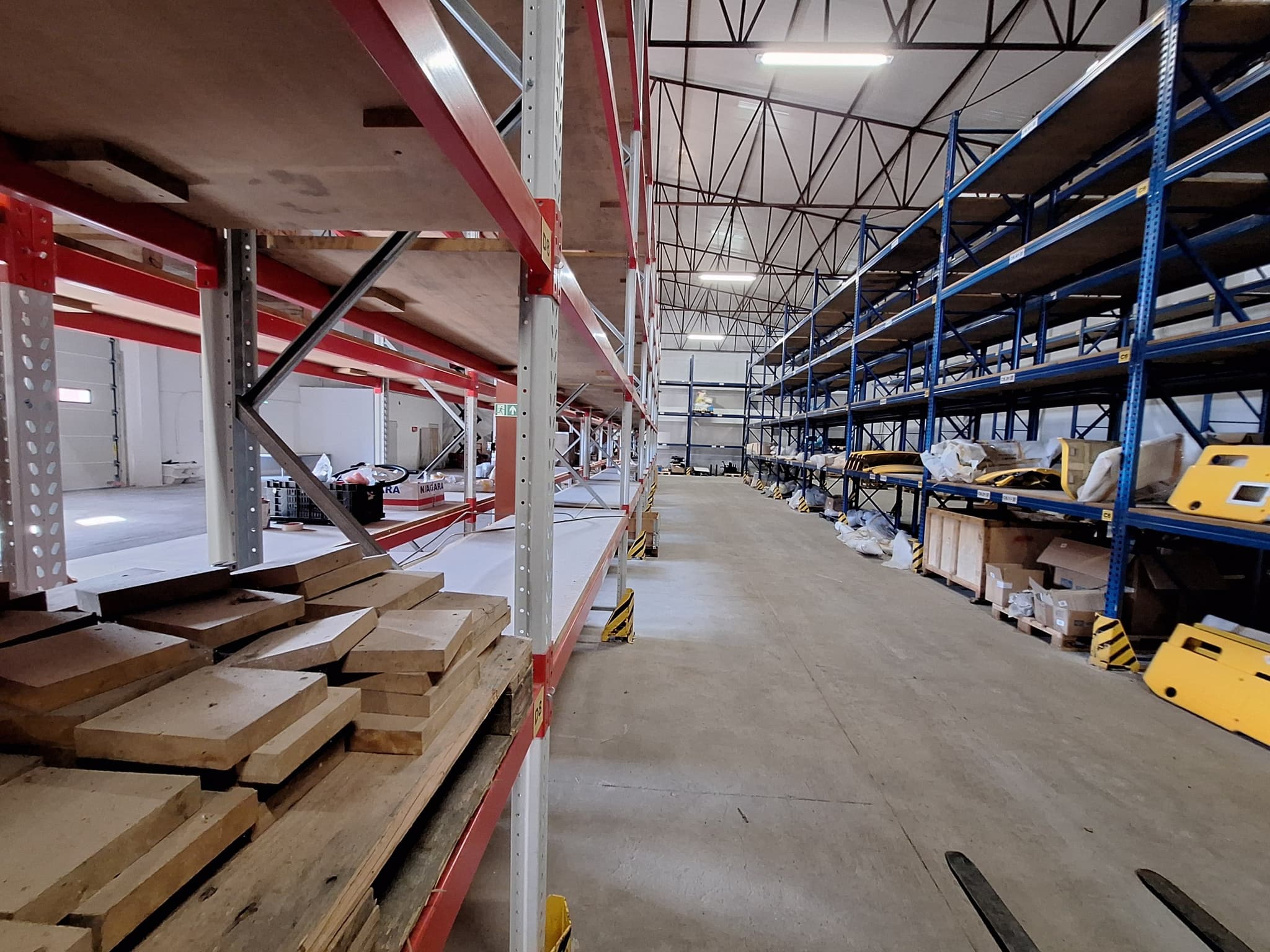 Red-painted racking corridor holding large-format rail components sorted by SKU